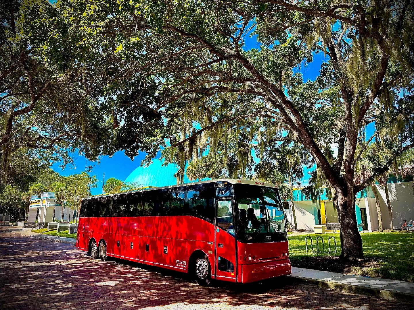 Welcome Transportation charter bus parked under oak trees