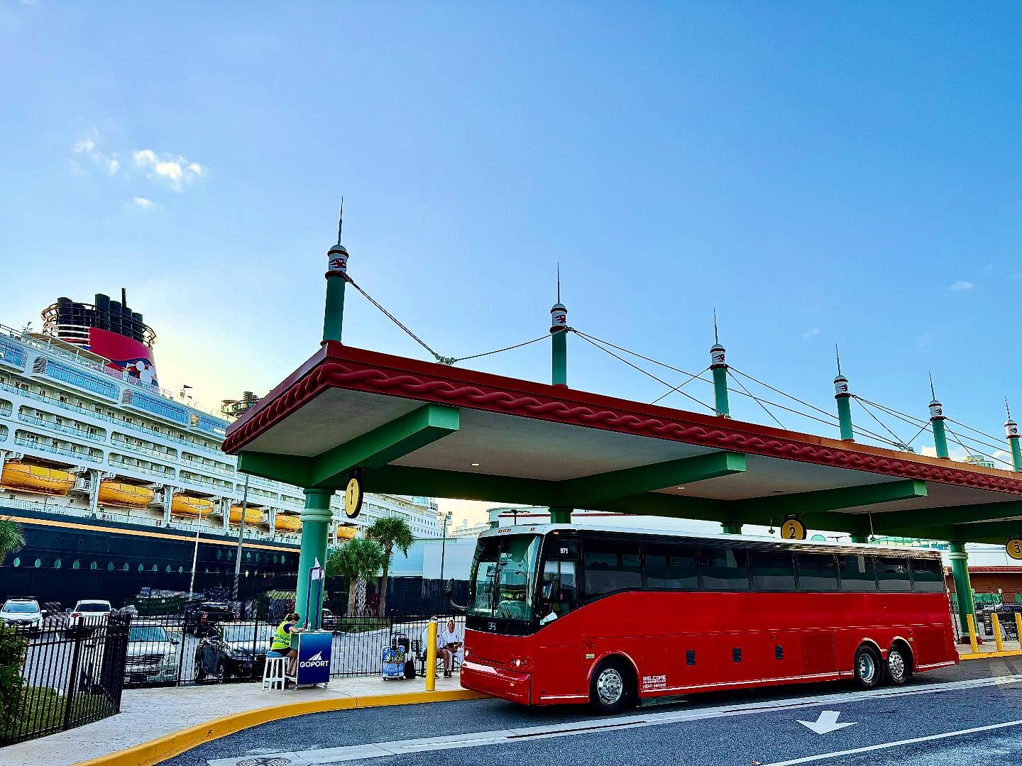 Welcome Transportation bus under the cruise terminal pavilion next to a Disney ship