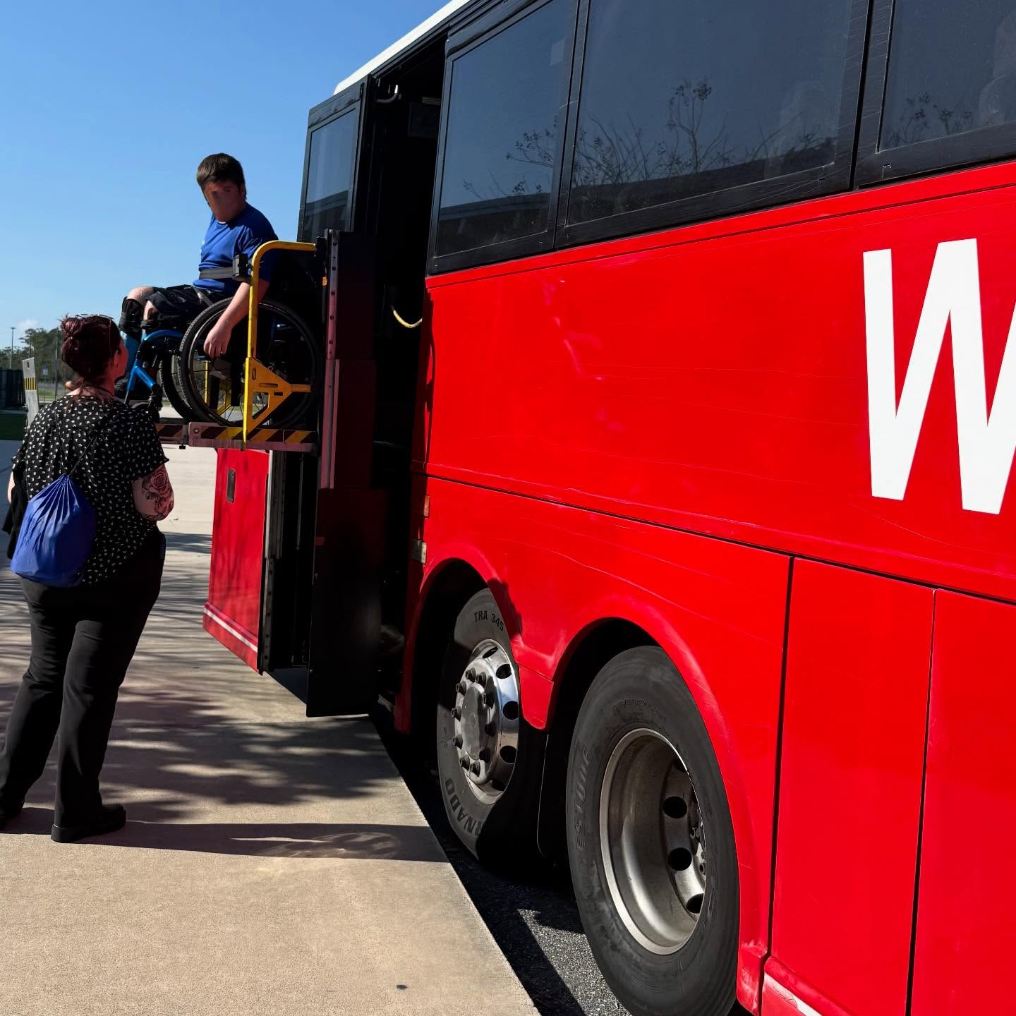Welcome Transportation staff assisting a passenger onto the wheelchair lift