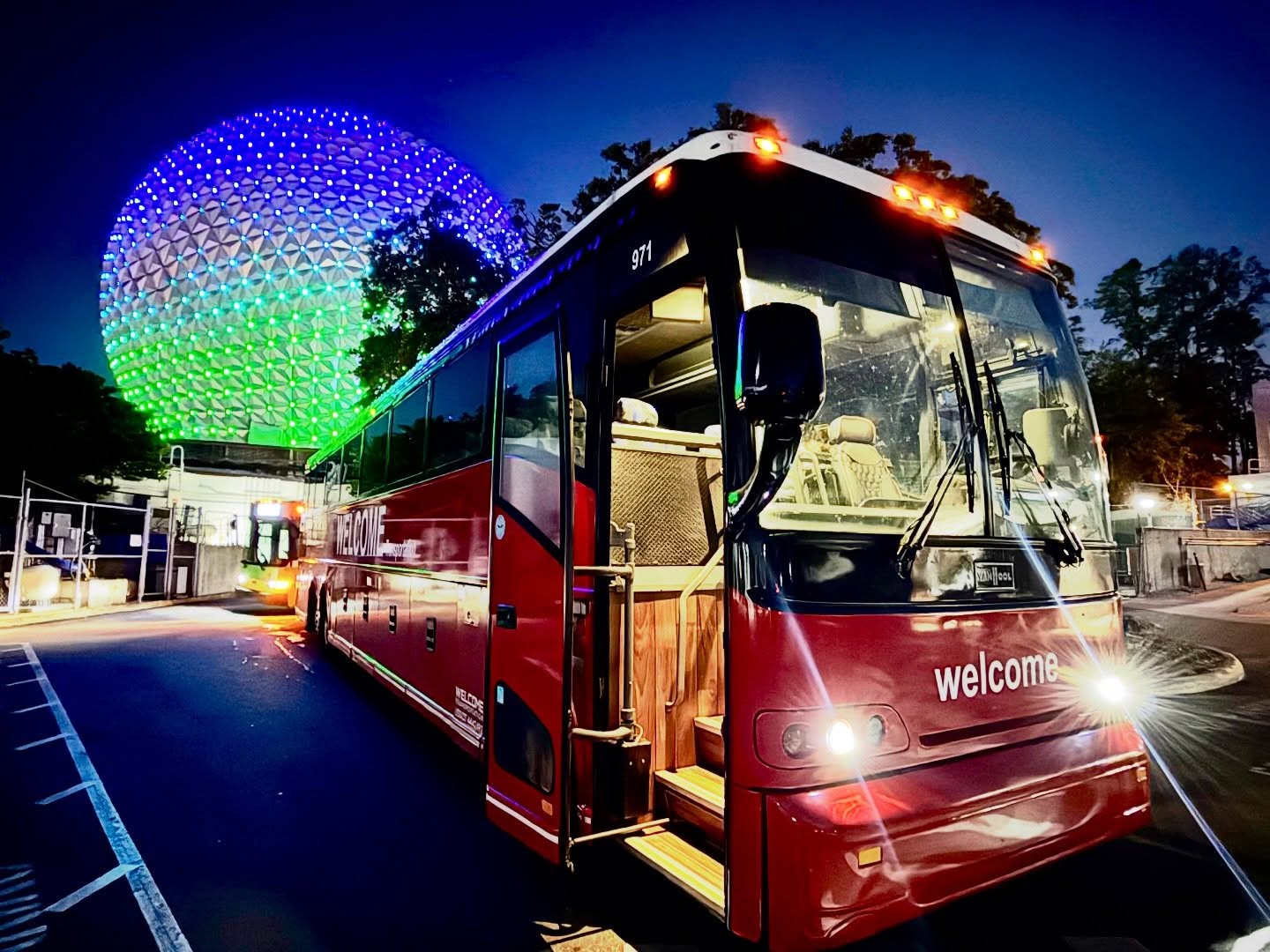 Welcome Transportation bus at night with Epcot's Spaceship Earth lit up behind it