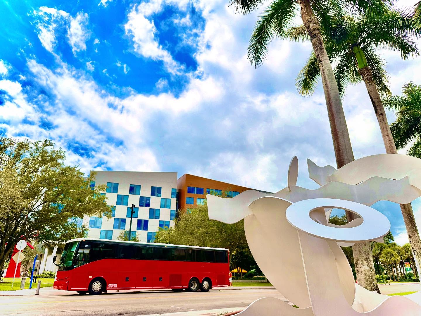 Welcome Transportation bus passing a public sculpture near a modern hotel