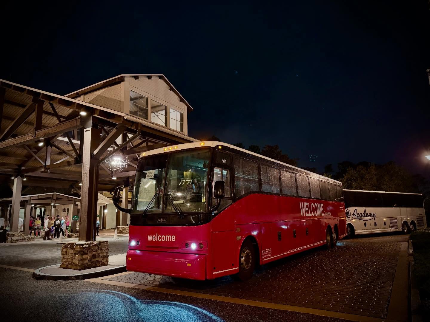 Welcome Transportation bus picking up guests at a lodge-style resort at night