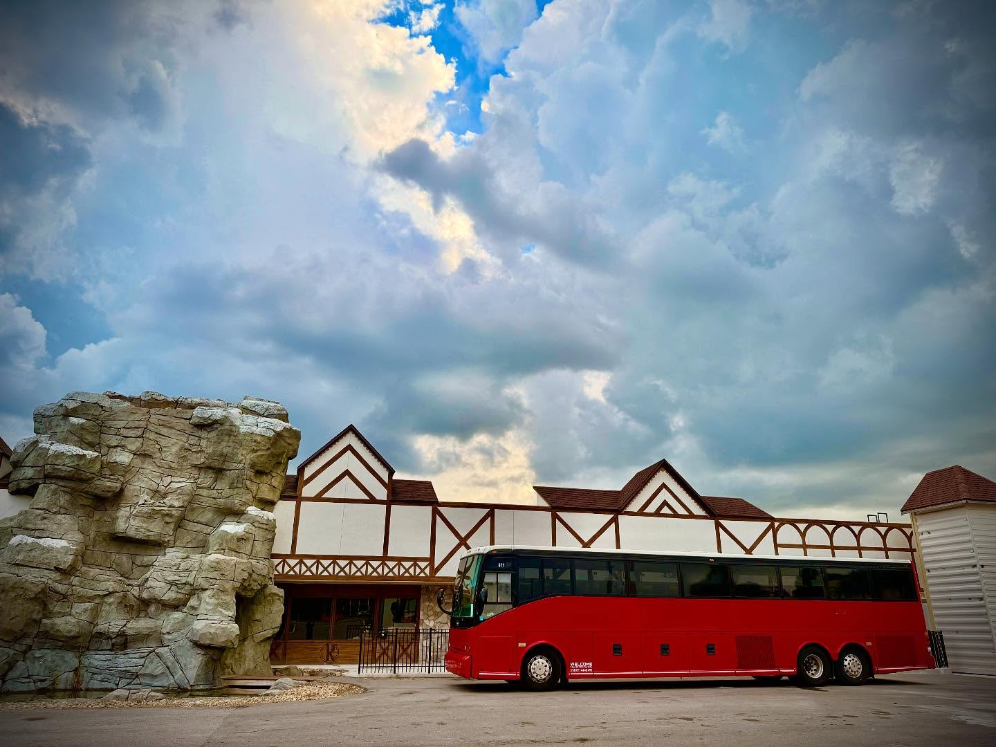 Welcome Transportation bus parked outside an alpine-style resort under a dramatic sky