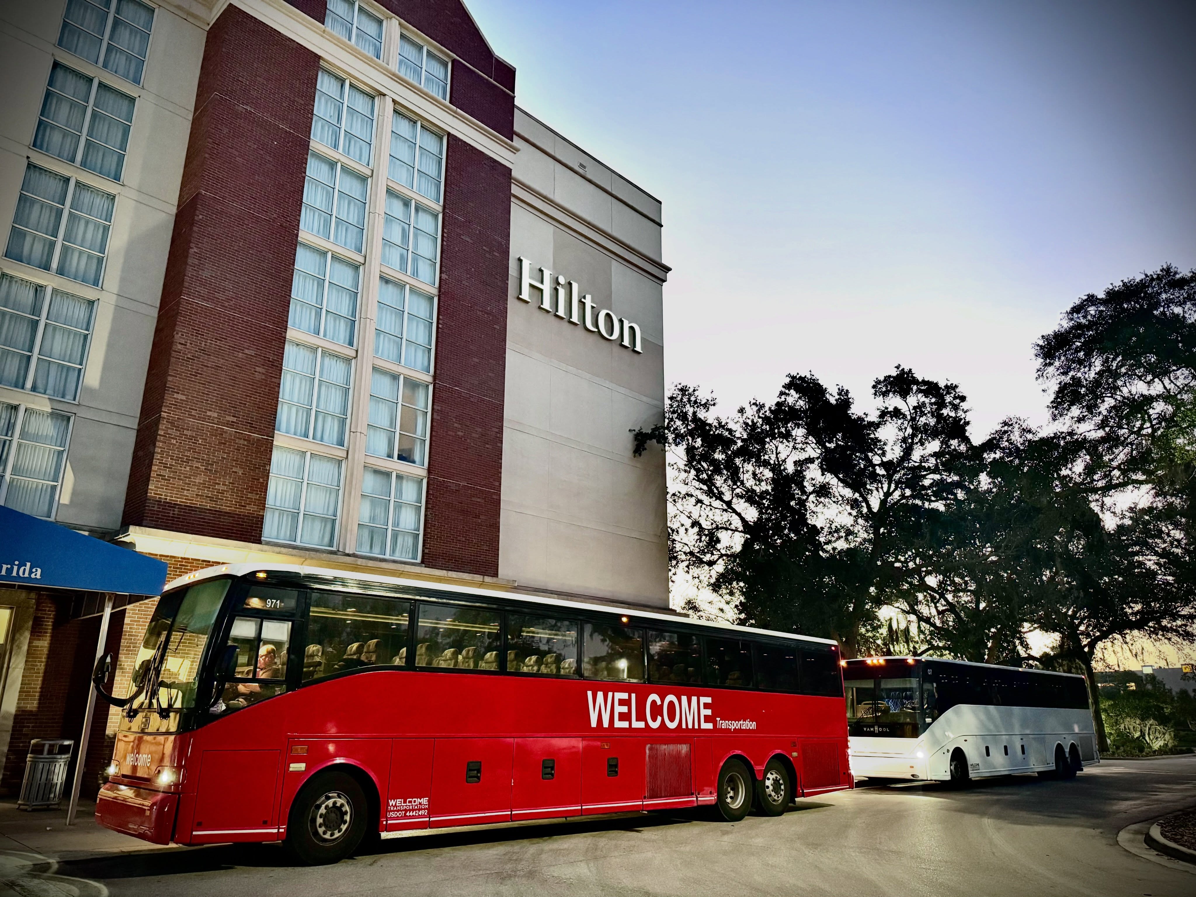 Welcome Transportation buses picking up guests at a Hilton hotel