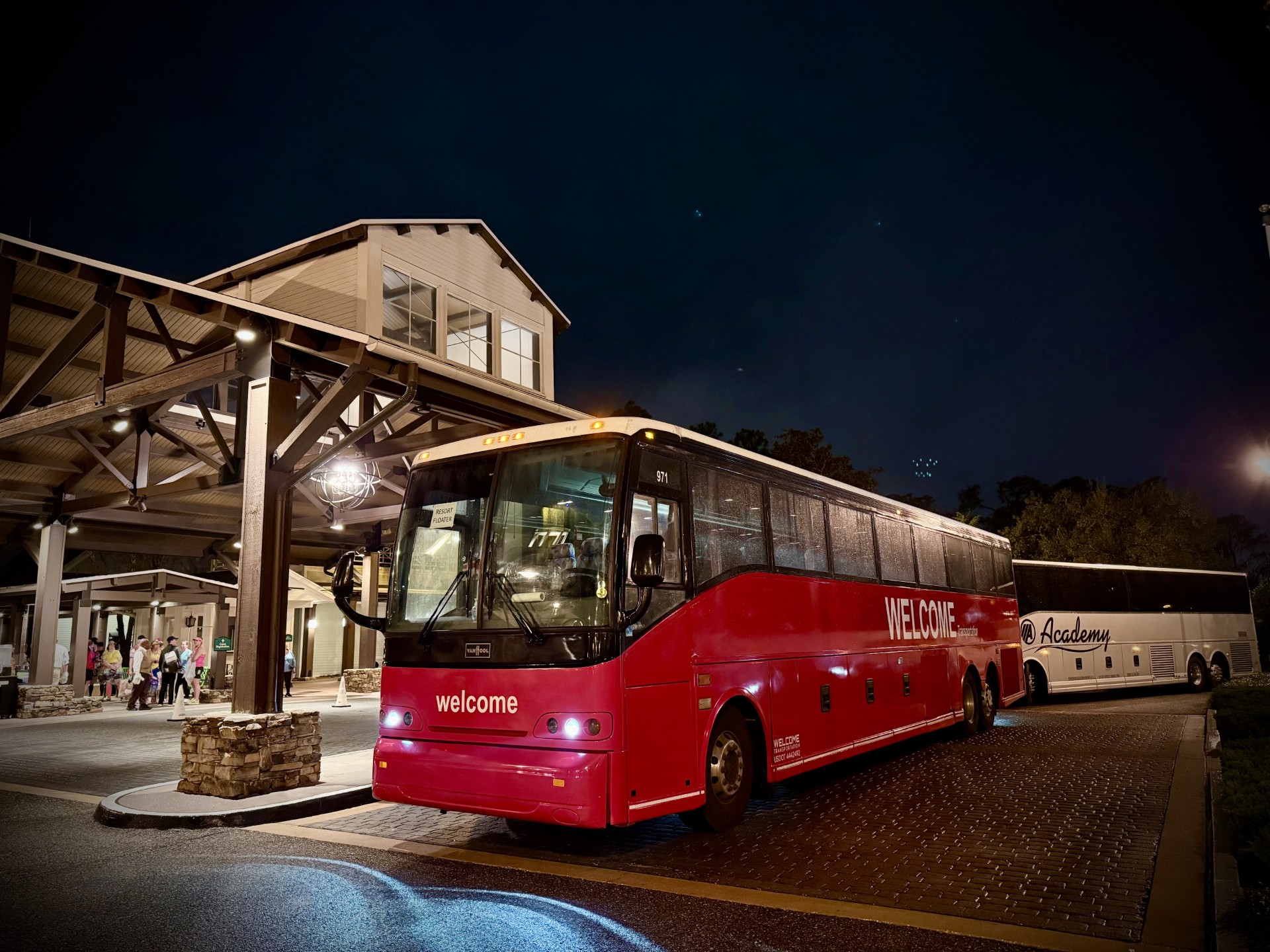Welcome Transportation bus picking up guests at a resort porte-cochere at night