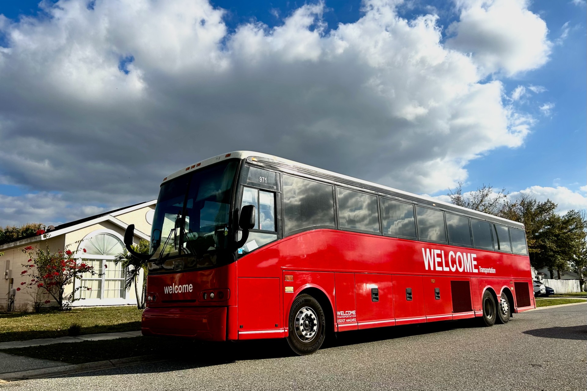 Welcome Transportation bus parked on a residential street under a dramatic cloudy sky
