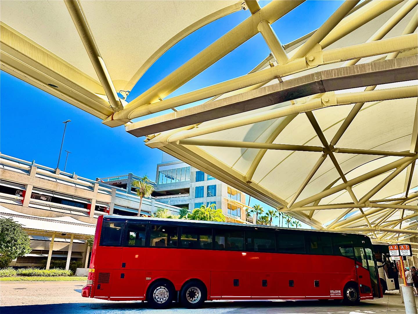 Welcome Transportation bus under an airport terminal canopy