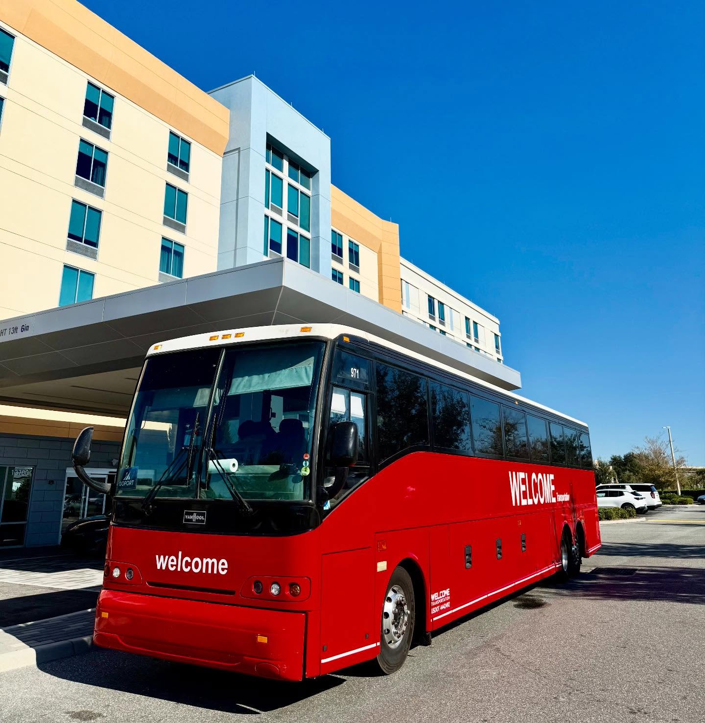 Welcome Transportation bus parked under a hotel entrance canopy