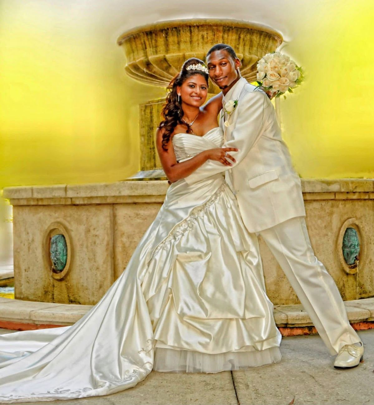 Bride and groom embracing in front of a stone fountain