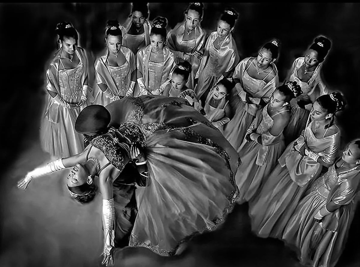 Overhead black-and-white photograph of a young woman in a ball gown dipped backward by her dance partner, encircled by her court